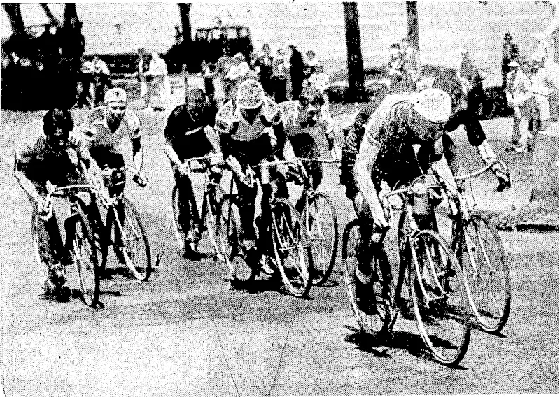 H. Binneman, of South Africa, leading in the 100 kilometres cycle race, which he won, at the Empire Games at Sydney on February 12. Partially obscured by Binneman is the young New Zealander, J. Brown, who was only defeated by six inches in the final sprint to the winning post. E. Triricr, another New Zealander, is seen at the tail of the field. (Evening Post, 26 February 1938)