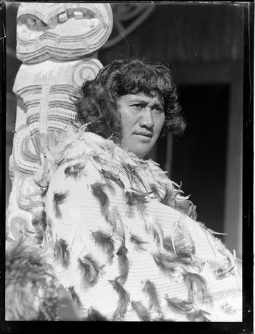 Image: Portrait of Pura Hohepa Konui sitting next to a carved pou at Otūkou marae, Lake Rotoaira