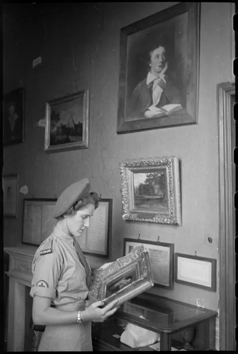 Miss E Garvey examines a painting of Lord Byron in the Keats House in Rome, Italy, World War II - Photograph taken by George Kaye