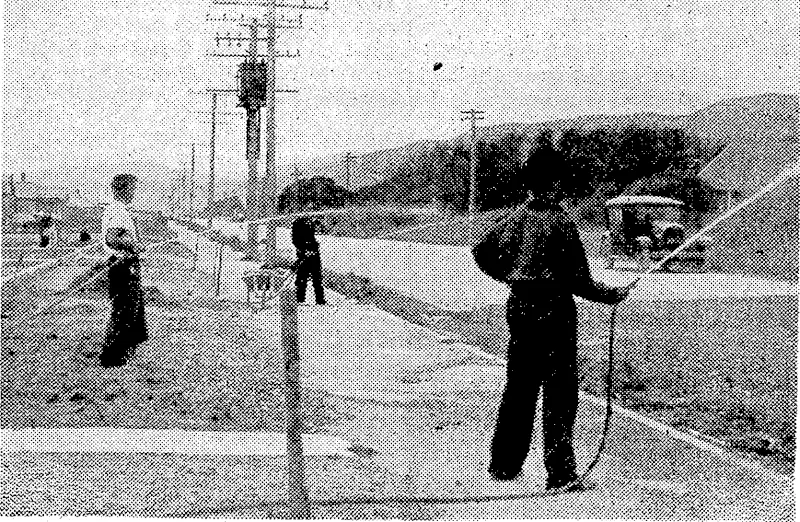 Residents of'Waiwhetu Road, Lower Hutt, watering the road in ifront t.r ■ r J■ , j y Ai j j. 7- '•■ •• '!■'■ • Ajt oftheir homes'tokeep down the dust which arises from passing traffic. (Evening Post, 24 February 1939)