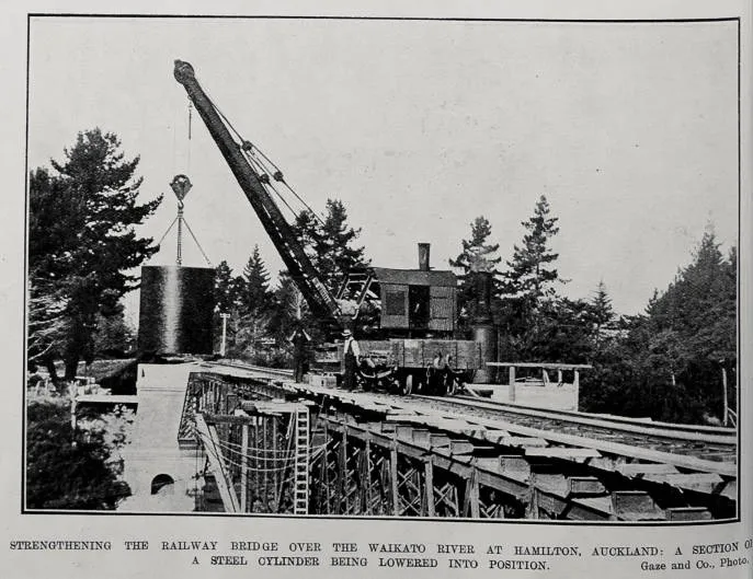 STRENGTHENING THE RAILWAY BRIDGE OVER THE WAIKATO RIVER AT HAMILTON, AUCKLAND: A SECTION OF A STEEL CYLINDERS BEING LOWERED INTO POSITION