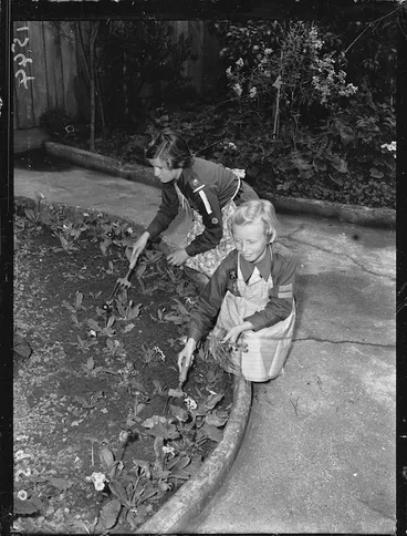Image: Girl Guide, and a Brownie, working in a garden during Bob a Job Week