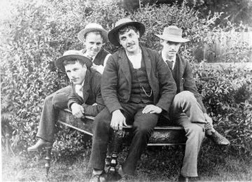 Image: Four young men sitting on a table outside