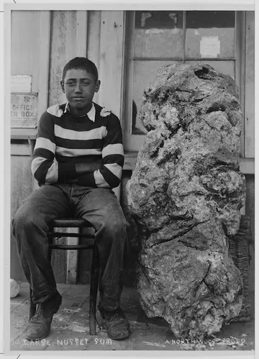 Image: Boy seated by a large nugget of Kauri gum