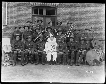 Image: Group portrait of the Kiwi entertainment orchestra with David Alexander Kenny in a pierrot costume