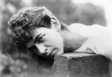 Image: A theatrical scene of a man with his head on an execution block