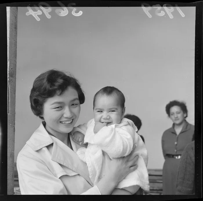 A member of a visiting Japanese youth delegation holds an infant during a visit to Waiwhetū