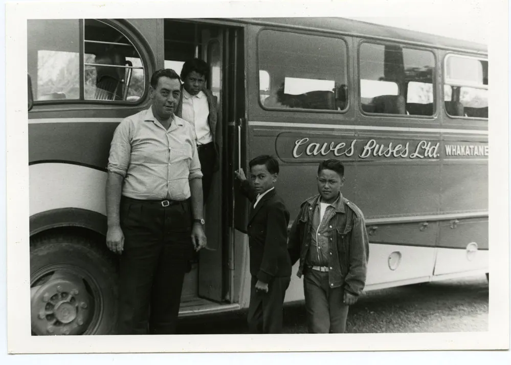 Unknown man and boys beside a bus