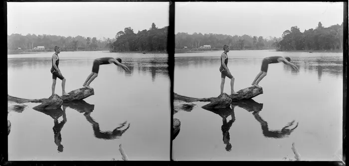 Two young men wearing bathing costumes, diving from a log in the Owaka River, Catlins District, Otago Region