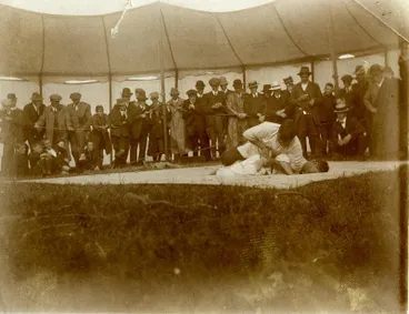 Image: Two men wrestling in front of spectators