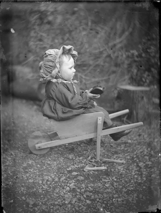 [Edgar or Owen Williams?], sitting in a toy wheelbarrow, location unidentified