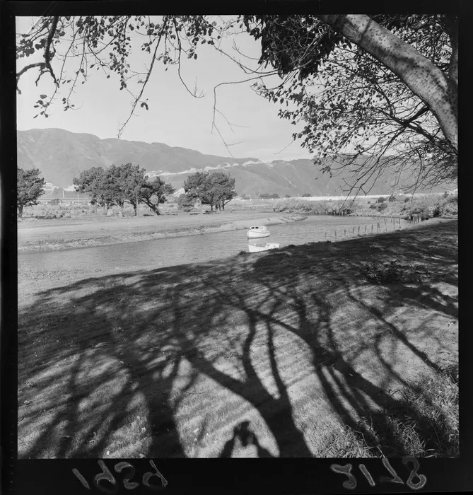 Boat on pond in park, Gear Island, Petone, Wellington Region, with Wainuiomata Hill Road in background