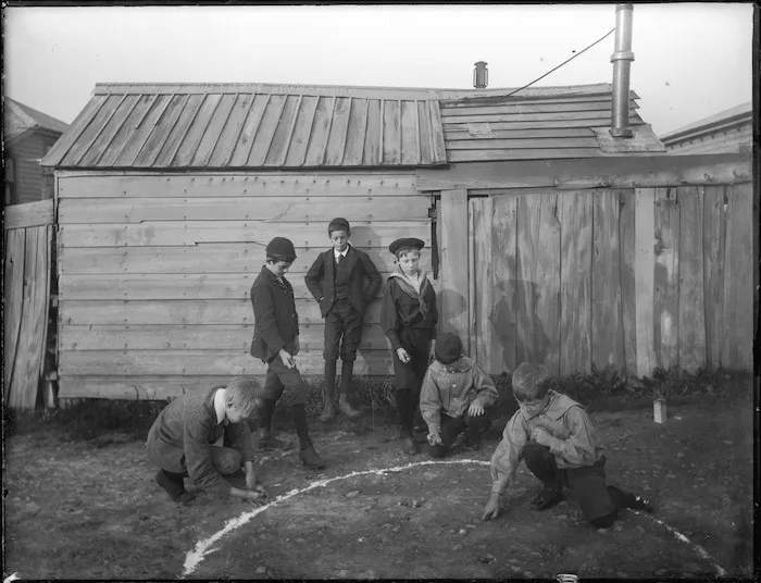 Six boys playing marbles outside