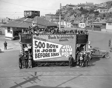 Image: A tram, full with children, advertising the objective "500 boys in jobs before Xmas", Wakefield Street, with Oriental Parade in background