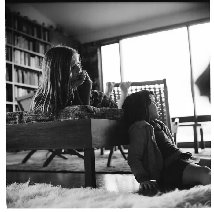 Two young girls watching TV inside a house in an unidentified location