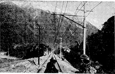 Image: THE ELECTRIFIED PERMANENT WAY OUTSIDE THE OTIRA TUNNEL, SHOWING OVERHEAD WIRES, SNOWY MOUNTAINS IN BACKGROUND. (Evening Post, 01 August 1923)