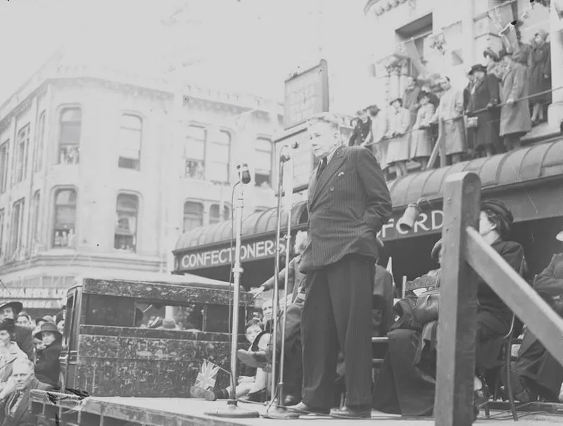 Celebrations. Crowd at WWII, Victory over Europe ( VE ) Day Celebration. Held 9 May 1945, Man Making Speech from the Back of a Truck. Colombo Street by the United Service Hotel, at the High Street Corner. Christchurch, Canterbury, New Zealand.