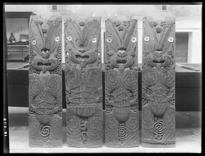 [Four poupou (carved panels) leaning against Te Toki a Tapiri waka]