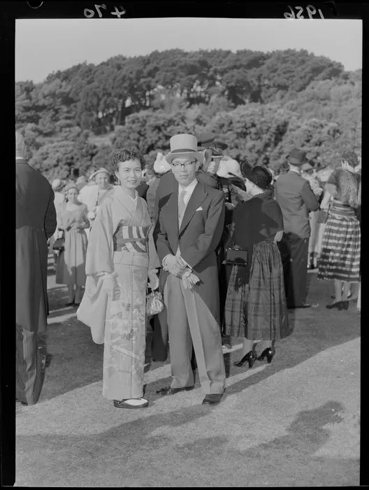 Finely dressed dignitaries J Takeno, the Change d'Affaires for Japan, and his wife, who are dressed up and at a garden party on the front lawn of Government House, Wellington, including top hat, suit, kimono, gloves and glasses