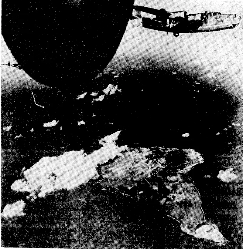 Liberators of the VnUed States Strategic Air Force send their bombs crashing down on Iwo Jima, Japanese air base in the Volcano Islands. Smoke and dust show that one of the two air strips has been aLJ \ T r°-°L P CYn De<^feFI 15' The dark oval at the upper left of the picture is the aileron of the Liberator from which the photograph ivas taken. On the nearest tip of the island is one of the volcanoes after which the group is named. (Evening Post, 04 January 1945)