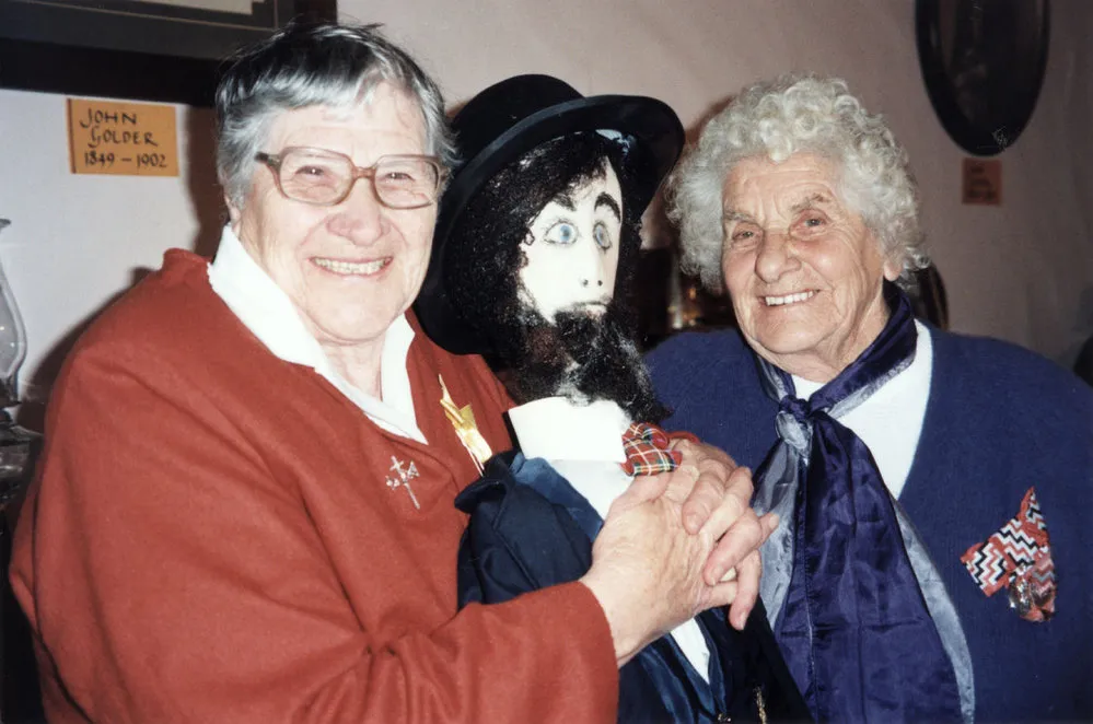 John Golder's grand-daughters present figure of John to the cottage museum.