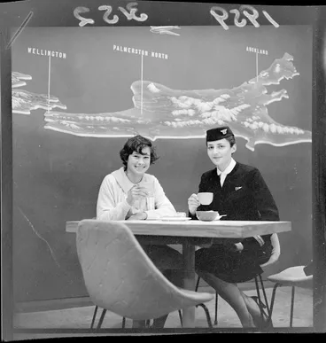 Image: Unidentified air hostess and passenger sitting at table, enjoying their refreshments, at the Wellington airport cafeteria