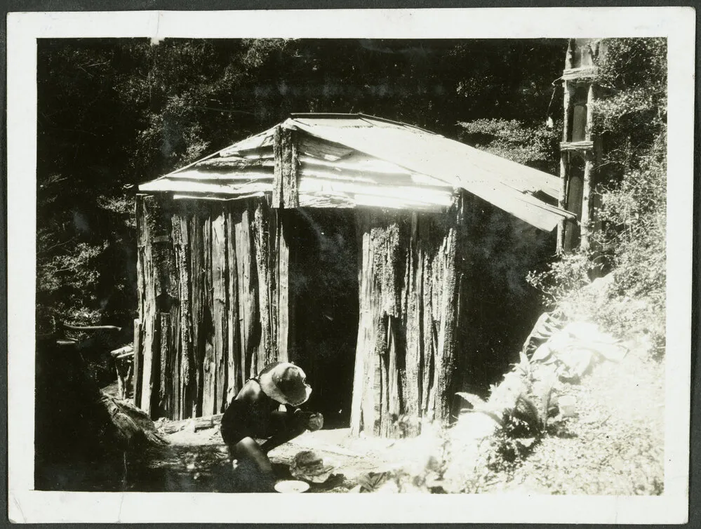 Tawhai Hut. [Image of a man crouching outside a wooden hut.]