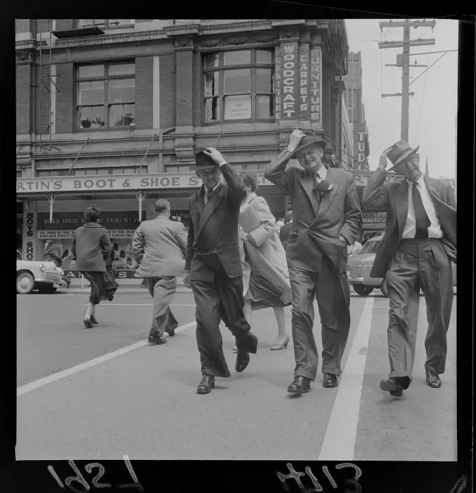 Men holding their hats in a Wellington wind