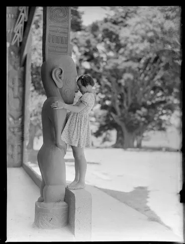 Image: Summer Child Studies series, child performs a hongi with a carved figure at Te Whare Runanga, Waitangi Treaty Grounds