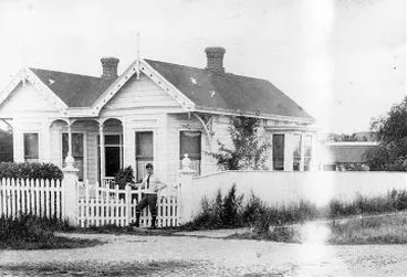 Image: Charles Haigh standing at the gates of an unidentified house