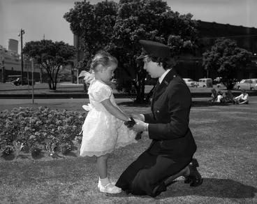 Image: Kneeling policewoman talking to a young girl in a park