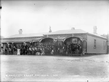 Image: Members of a band and a group of people standing outside outside the house of Charles Waitara, at Parihaka