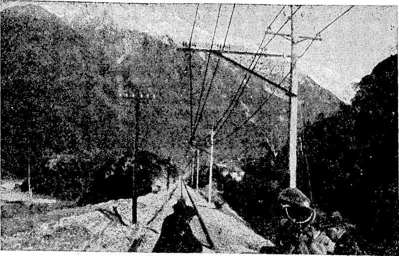 THE ELECTRIFIED PERMANENT WAY OUTSIDE THE OTIRA TUNNEL, SHOWING OVERHEAD WIRES, SNOWY MOUNTAINS IN BACKGROUND. (Evening Post, 01 August 1923)