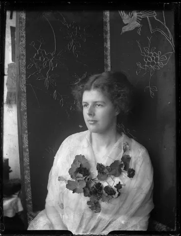 Image: Woman seated in front of a decorative screen