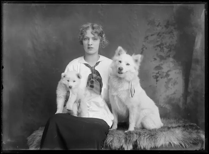 Studio portrait of an unidentified young woman with two husky dogs, including a puppy, possibly Christchurch district