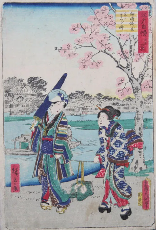 Two women walk beside a river holding a stick between them from which baskets are suspended.