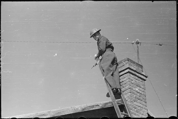 Corporal W A Lamont takes lead of hose up a ladder during training of NZ Maadi Camp Fire Unit, Egypt, World War II - Photograph taken by George Bull
