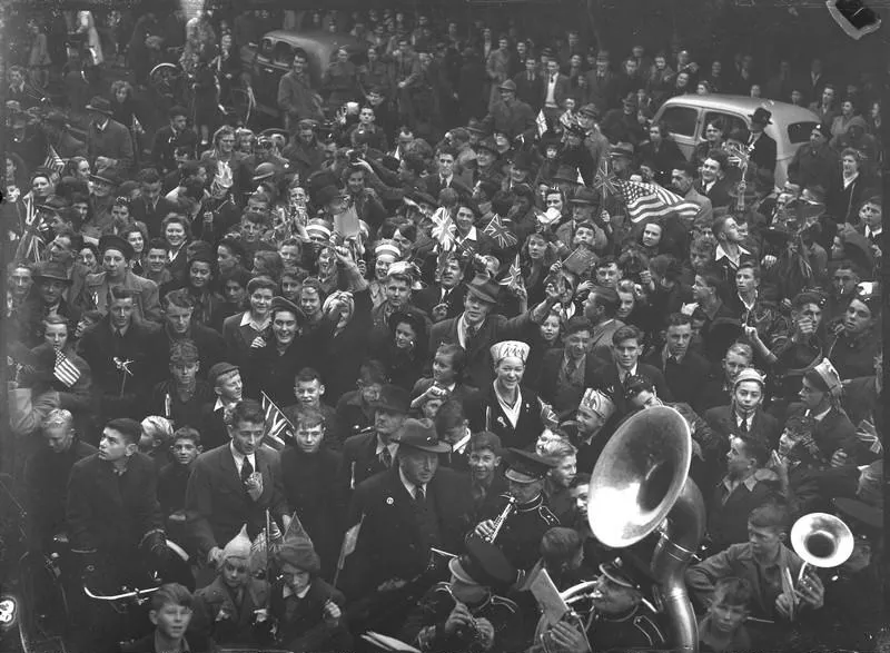 Celebrations. Crowd at WWII, Victory over Europe ( VE ) Day Celebration. Held 9 May 1945, Band at Bottom Passing Through. Christchurch, Canterbury, New Zealand.