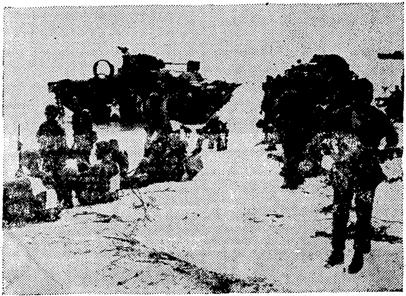 tf.S. Marines relax on a beach at Saipan Island, major Japanese supply jbase in thft Marianas Group cf the Central Pacific, after storming ashore to establish a beachhead on June 14. Two American amphibious tanks, knocked out during the beaching operations;, lie offshore. (Rodney and Otamatea Times, Waitemata and Kaipara Gazette, 03 January 1945)