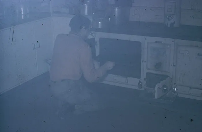 Eric Clague rescuing burnt biscuits, Campbell Island