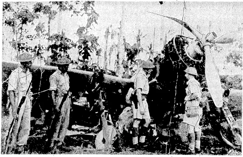 While two Fijian soldiers stand on guard, New Zealand officers of the-, First Battalion of Fiji Infantry, fighting in the South Pacific,-examine a Japanese Zero plane shot down during the attack which led I to the capture of the Vila air strip on Kularnbangna Island. .' ■ (Evening Post, 01 March 1944)