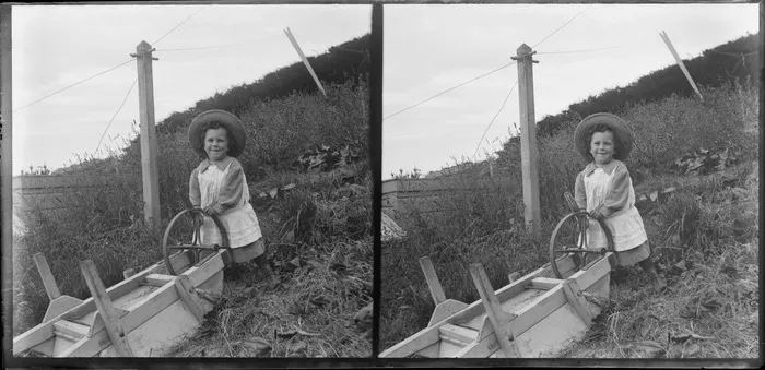 Unidentified young child [Edwin or Owen Williams?] playing with the wheel of an upturned wheelbarrow, Kew, Dunedin