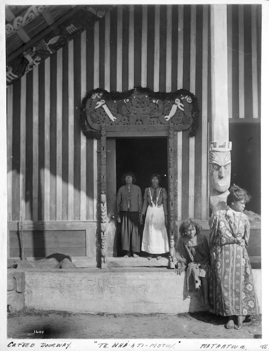 Maori group alongside the entrance to Te Whai-a-te-Motu meeting house, Mataatua