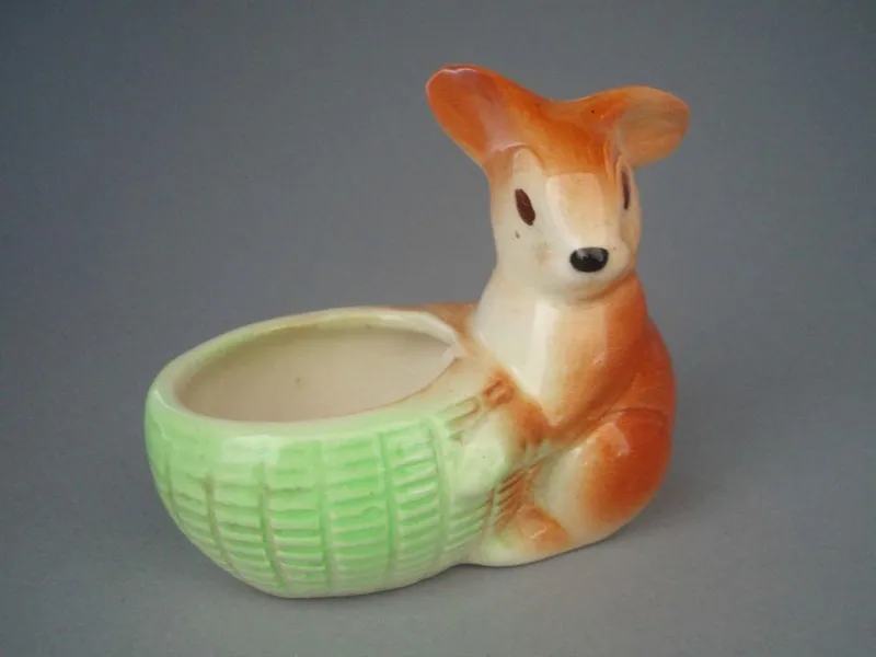 Easter egg cup - rabbit - Egg cup in the shape of a rabbit holding a basket. Designed to hold an Easter egg. Airbrushed in brown, cream, green and black. Clearglazed.