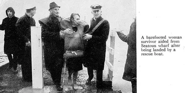 Image: A barefooted woman survivor aided from Seatoun wharf after being landed by a rescue boat