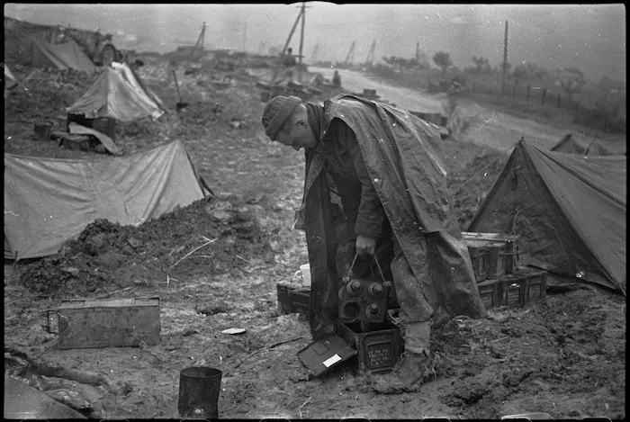 Mud spattered New Zealander opens a new box of 25 pounder ammo on the Italian Front, World War II - Photograph taken by George Kaye