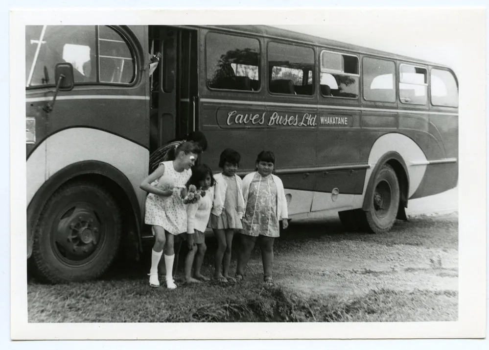Five Maori children beside a bus