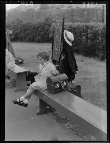 Image: Child at a bowls tournament with scoreboard and bowls cases