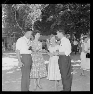 Image: Personalities at the Tauherenikau Racecourse with two unidentified couples looking over race programme, Wairarapa District