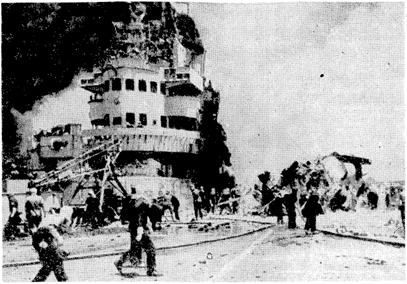 Firefighters on a British aircraft-carrier in the Pacific after a Japanese suicide plane had crash-landed on the flight deck. Little damage was done, and the carrier was out of action for less than tivo hours. (Evening Post, 20 July 1945)
